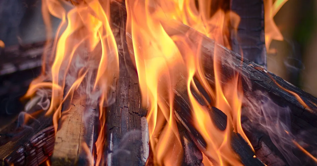 Orange flames burning stacked wood boards, close view