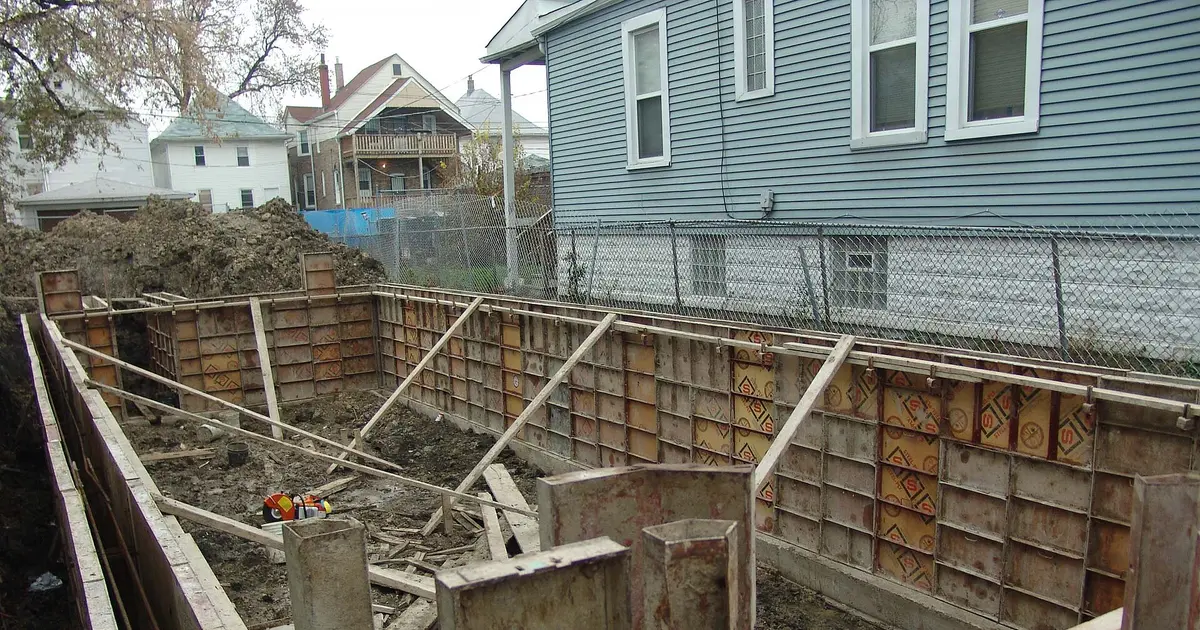 Concrete foundation excavation lined with steel and plywood formwork panels braced with timber