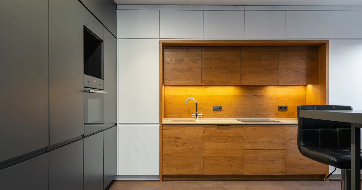 Modern kitchen with timber-faced cabinets and white wall units beside dark tall units