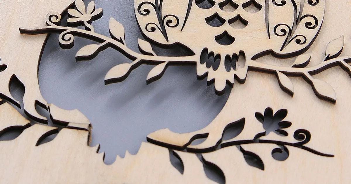 Intricately laser-cut owl design in light plywood, showing the fine cut lines and layered edges